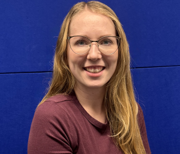 Blonde Frau vor blauer Wand.